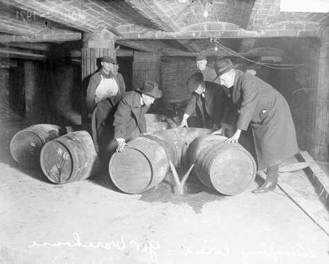 Agentes do governo no ato de confiscar e descartar bebidas clandestinas (Chicago, 1921).